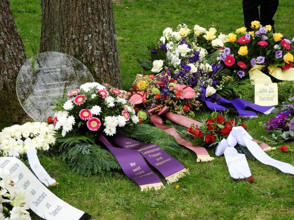 Gedenktafel zur Erinnerung an lesbische Frauen im KZ Ravensbrück mit Blumengestecken